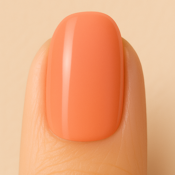 Close-up of a finger with a peach-colored nail on a beige background