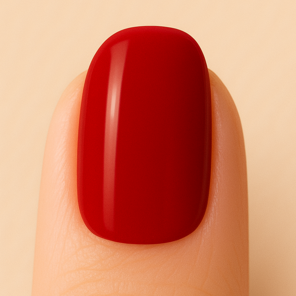 Red nail polish on a finger against a beige background