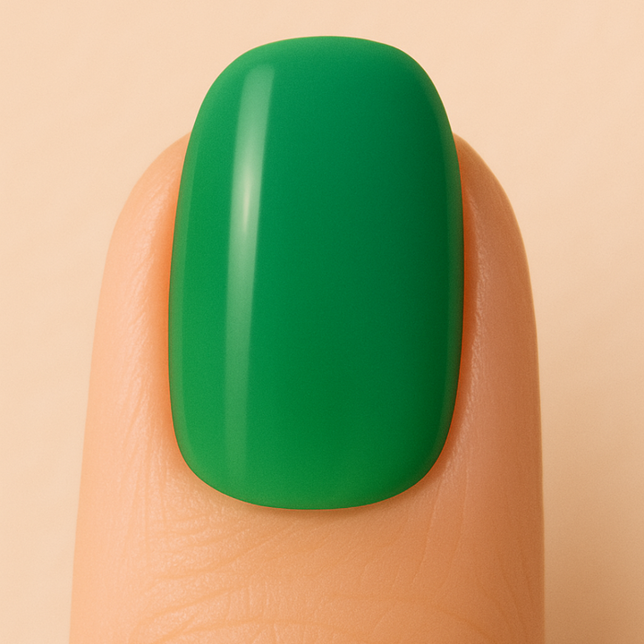 Green gel nail polish on a finger against a beige background