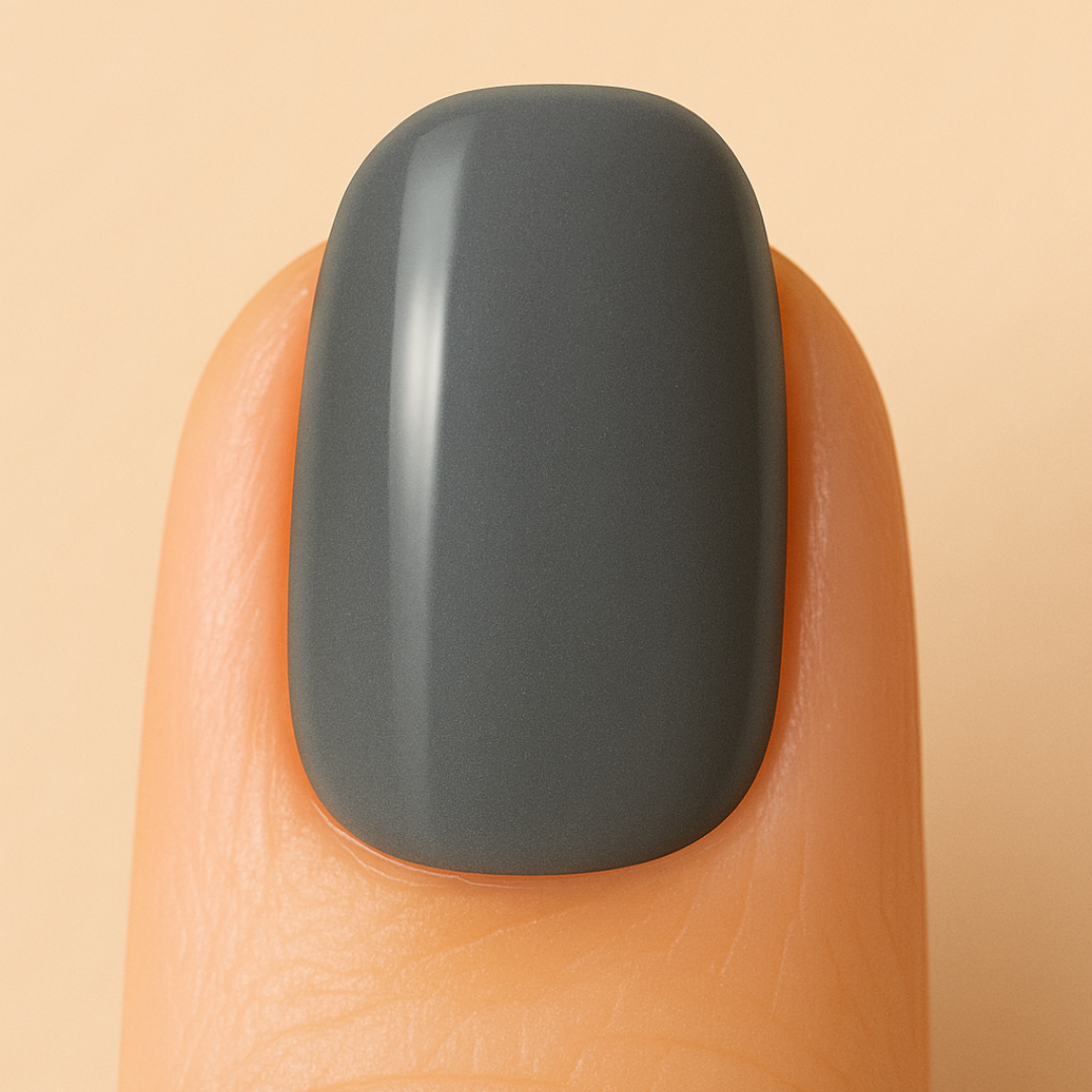 Dark grey gel nail polish on a fingernail against a beige background