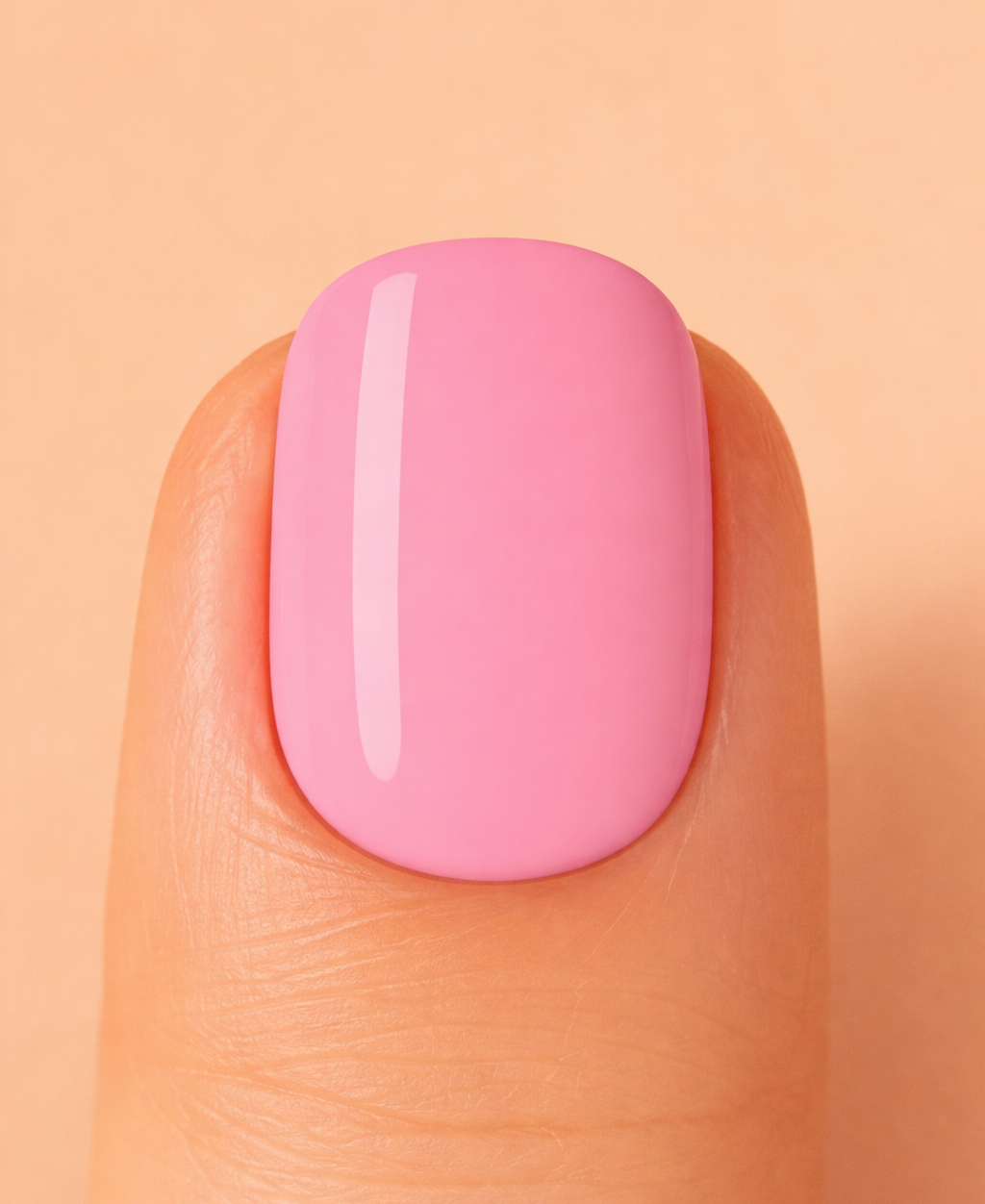 Close-up of a pink nail on a peach-coloured background